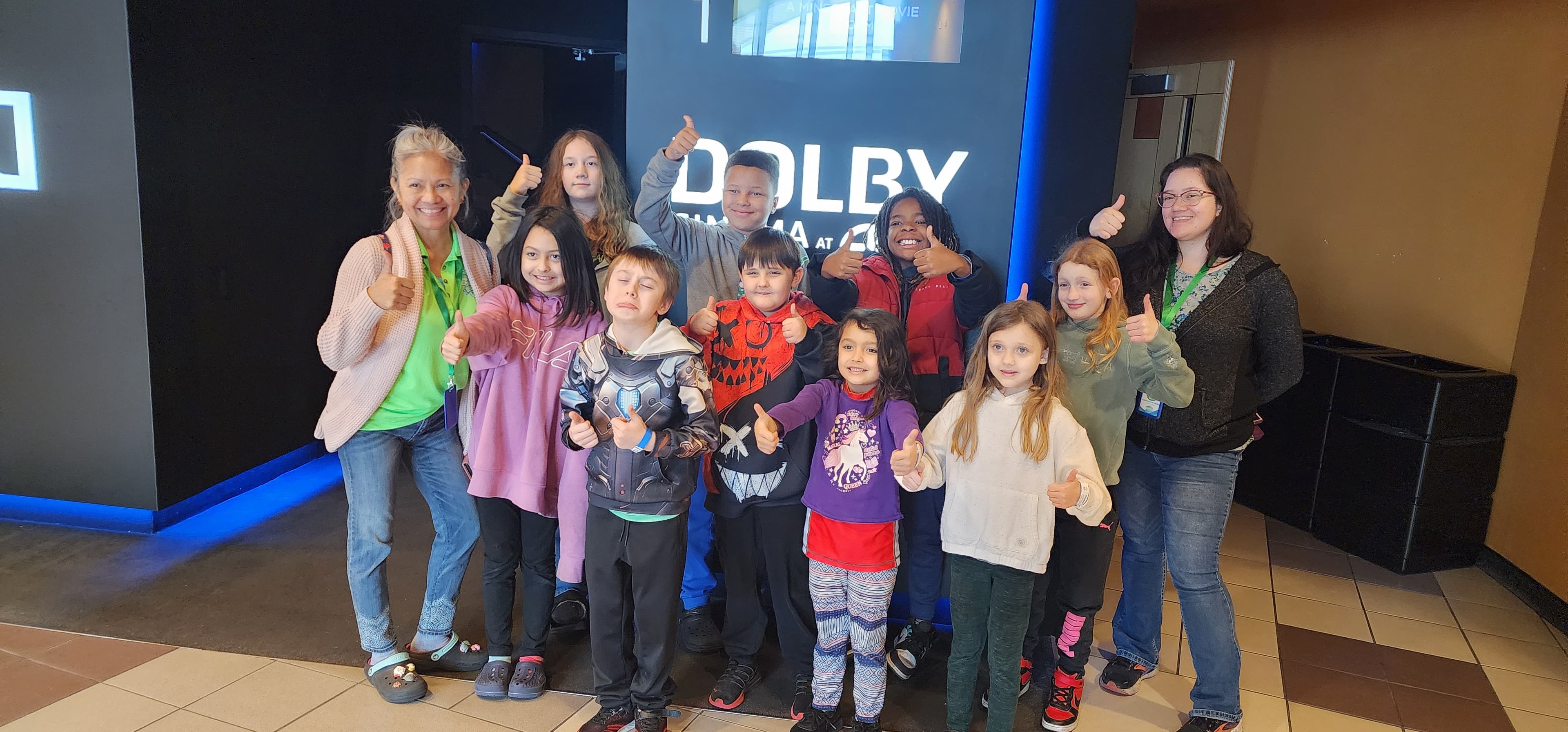 Campers and staff giving thumbs up at a movie theater