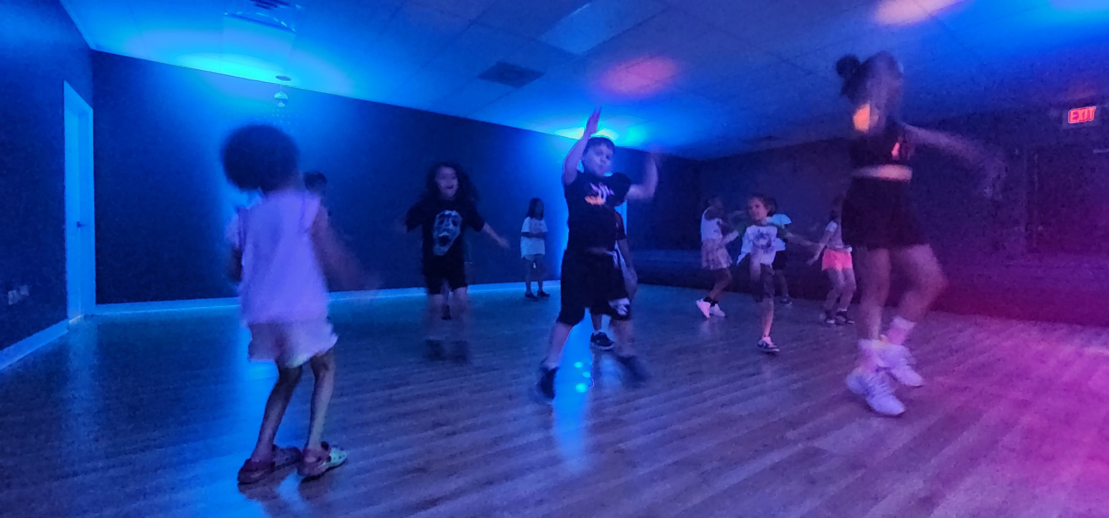 Campers dancing in a room with blue lights