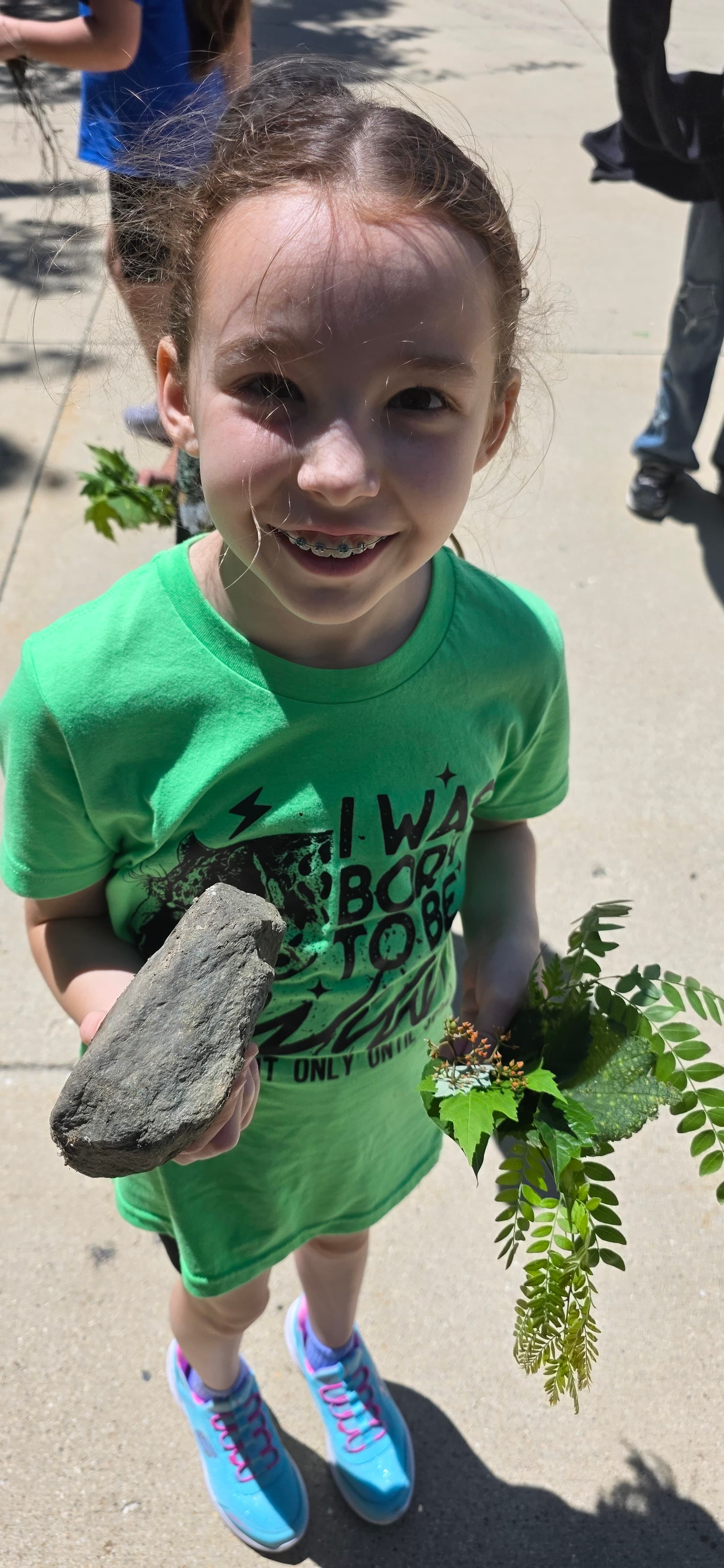 Camper holding a fern and rock found on a nature outing